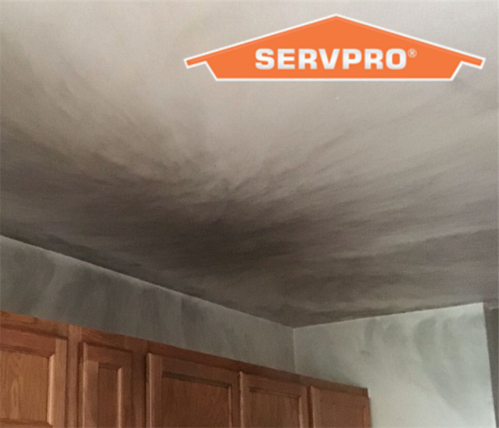 black smoke and soot left on the ceiling in the kitchen with a green ceiling above kitchen cabinets.