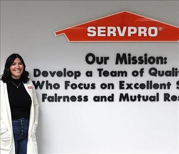 Office manager standing in front of SERVPRO's mission statement