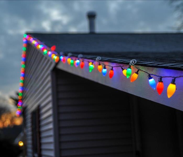 Christmas lights containing an assortment of colors on the roof of a house in the evening time. 