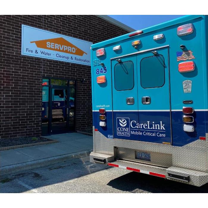 brick office building with SERVPRO sign with a light blue and dark blue ambulance from Cone Health.