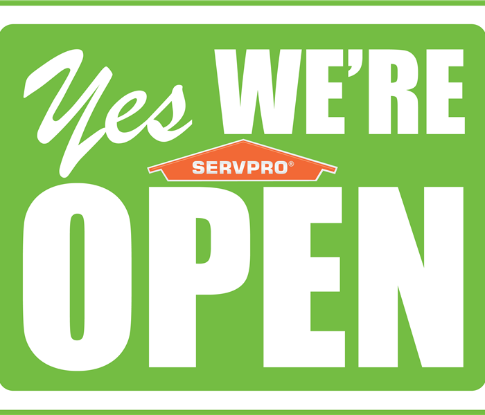 Yes We're Open sign in white letters with green background and servpro logo